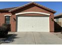 View of the two-car garage featuring a white door and exterior wall mounted sconces at 36610 W Picasso St, Maricopa, AZ 85138