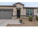 Home exterior featuring well-manicured landscaping, neutral stucco, grey garage door, and a decorative flower pot at 38101 W Santa Maria St, Maricopa, AZ 85138