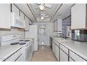 Bright kitchen featuring white appliances, a double ceiling fan and plenty of cabinet and counter space at 5223 W Acoma Dr, Glendale, AZ 85306