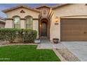 Inviting entryway featuring a dark wooden door, arched entrance, and manicured landscaping at 10772 W Woodland Ave, Avondale, AZ 85323