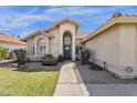 Beige single-Gathering home featuring a front entrance with an arched alcove and beautiful desert landscaping at 12125 N 91St Way, Scottsdale, AZ 85260