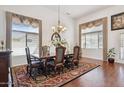 Formal dining room with a hardwood floor, elegant chandelier, and large windows with decorative curtains at 16428 N 39Th Pl, Phoenix, AZ 85032