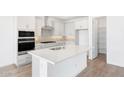 Modern white kitchen featuring stainless steel appliances, a spacious island with a sink, and ample cabinet space at 17264 W Via Dona Rd, Surprise, AZ 85387