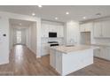 Bright, open-concept kitchen showcasing white cabinetry, stainless steel appliances, and an island with quartz countertops at 17295 W Via Dona Rd, Surprise, AZ 85387