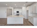 Bright, open-concept kitchen showcasing white cabinetry, stainless steel appliances, and an island with quartz countertops at 17295 W Via Dona Rd, Surprise, AZ 85387