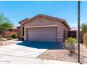 Side view of a well-maintained home showcasing a two-car garage and desert landscaping at 17633 W Wind Song Ave, Goodyear, AZ 85338
