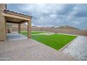 Backyard featuring artificial turf, gravel, a paved walkway, and a covered patio at 25437 W Mahoney Ave, Buckeye, AZ 85326