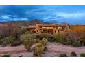 Exterior view of the home nestled in a desert landscape with mountain views at dusk at 40478 N 108Th Pl, Scottsdale, AZ 85262