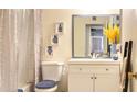 Bright bathroom featuring a modern vanity, decorative wall art, toilet with blue seat, and a shower with curtain at 7217 W Claremont St, Glendale, AZ 85303