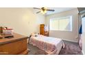 Well-lit bedroom with a bed, wooden dresser, a ceiling fan and ample natural light from the window at 7217 W Claremont St, Glendale, AZ 85303