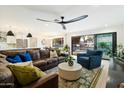 Bright living area with sliding glass doors to the pool, featuring a large sofa, stylish decor, and a unique ceiling fan at 9331 S Lakeshore Dr, Tempe, AZ 85284