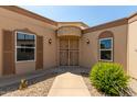 Close exterior view of the front entrance featuring a metal security gate, decorative molding, sconces, and shuttered windows at 13677 N 108Th Dr, Sun City, AZ 85351