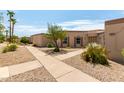 Exterior shot of desert-landscaped home featuring tan stucco, mature landscaping, and multiple walkways in front yard at 13677 N 108Th Dr, Sun City, AZ 85351