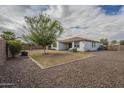 Large backyard featuring desert landscaping, mature trees, block fencing, and covered patio at 18385 W Devonshire Ave, Goodyear, AZ 85395