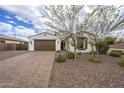 Inviting single-story home showcasing a brown two-car garage, desert landscaping, and a brick paver driveway at 18385 W Devonshire Ave, Goodyear, AZ 85395