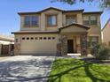 Two-story home featuring a two-car garage, manicured lawn, and a mix of stone and stucco finishes at 28273 N Castle Rock Dr, San Tan Valley, AZ 85143