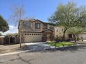 Two-story home featuring a two-car garage, manicured lawn, and a mix of stone and stucco finishes at 28273 N Castle Rock Dr, San Tan Valley, AZ 85143