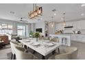 Bright, open-concept living and dining area with modern lighting and updated kitchen featuring white cabinets at 41260 W Palmyra Ln, Maricopa, AZ 85138