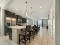 Open-concept kitchen with an extended island, pendant lights, tile floors, and a seamless flow to the living area at 10419 W Papago St, Tolleson, AZ 85353