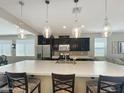 Modern kitchen boasts a large center island, pendant lighting, stainless steel appliances, and dark wood cabinetry at 10419 W Papago St, Tolleson, AZ 85353