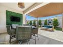 Inviting covered patio with dining table, chairs, TV and seating area for entertaining at 12047 E Sereno Rd, Gold Canyon, AZ 85118