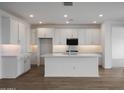 Bright, open kitchen boasts an island, white cabinets, modern appliances, and herringbone backsplash at 17310 W Via Dona Rd, Surprise, AZ 85387