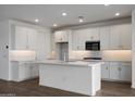 Bright kitchen features a central island, white cabinetry, stainless steel appliances, and decorative tile backsplash at 17310 W Via Dona Rd, Surprise, AZ 85387
