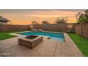 Backyard with a sparkling pool, fire pit, and lush green grass at 10024 E Tamery Ave, Mesa, AZ 85212