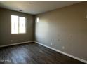 Bright bedroom featuring wood-look tile flooring, neutral paint, and a large window for natural light at 17558 W Lupine Ave, Goodyear, AZ 85338