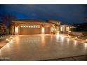 Attractive exterior with a three-car garage and a well-lit driveway at twilight at 17642 N Ironhorse Dr, Surprise, AZ 85374