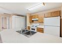 Cozy kitchen featuring wood cabinets, white appliances, and a peninsula sink at 3129 W Mohawk Ln, Phoenix, AZ 85027