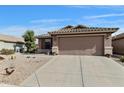 Attached two-car garage with concrete driveway and desert landscaping at 43870 W Baker Dr, Maricopa, AZ 85138