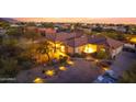 Desert property at dusk featuring landscape lighting, mature trees, and circular driveway at 9331 E Mclellan Rd, Mesa, AZ 85207