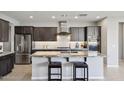 Open concept kitchen with a granite island, stainless steel appliances, dark cabinets, and bar stool seating at 13418 W Mayberry Trl, Peoria, AZ 85383