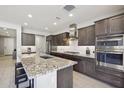 Modern kitchen featuring stainless steel appliances, dark cabinetry, and a granite-topped island with bar stool seating at 13418 W Mayberry Trl, Peoria, AZ 85383