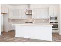 Gorgeous white kitchen with stainless steel appliances, tile backsplash, and a large center island with white countertops at 352 E Las Perlas Ln, San Tan Valley, AZ 85140