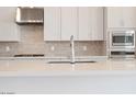 Close up of a modern kitchen with white cabinets, stainless steel appliances, and white countertop with stainless faucet at 352 E Las Perlas Ln, San Tan Valley, AZ 85140
