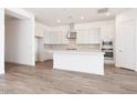 Bright, modern kitchen with white cabinets, stainless steel appliances, a large island and light wood-look flooring at 352 E Las Perlas Ln, San Tan Valley, AZ 85140