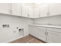 Well-lit laundry room boasts white cabinets, marble countertops, stainless faucet, and tile flooring at 3746 E Rochelle Cir, Mesa, AZ 85215
