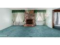 Cozy living room with a brick fireplace, lush green carpeting, and vintage green curtains at 4510 W Keim Dr, Glendale, AZ 85301