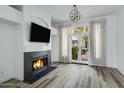 Cozy living room with fireplace, modern light fixture, and doors to the outdoor space at 4955 E Indian School Rd # 5, Phoenix, AZ 85018