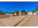 View of the home's exterior featuring an extended driveway and detached garages with painted brick at 1002 W Fairway Dr, Mesa, AZ 85201