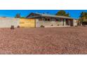 Single story home with neutral painted brick, desert rock yard, and wood accent fencing at 1002 W Fairway Dr, Mesa, AZ 85201