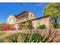 Beautiful home with a charming balcony, desert landscaping, brick retaining wall, and a bright blue sky at 15239 W Alexandria Way, Surprise, AZ 85379