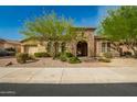 Charming home featuring a stone archway entrance, desert landscaping, and a well-manicured front yard at 18068 W Narramore Rd, Goodyear, AZ 85338