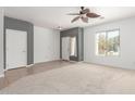 Open living room with neutral carpet, a ceiling fan, and views of the front yard at 24824 W Pueblo Ave, Buckeye, AZ 85326