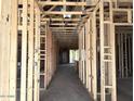 Unfinished interior view down a hallway showing the frame, electrical and plumbing at 5519 S 240Th Ln, Buckeye, AZ 85326