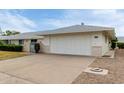 Charming single-story home with a two-car garage, manicured bushes, and small decorative entry gate at 12939 W Prospect Dr, Sun City West, AZ 85375