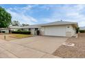 Charming single-story home with a two-car garage, manicured bushes, and small decorative entry gate at 12939 W Prospect Dr, Sun City West, AZ 85375