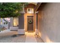 Inviting entryway with a dark wood door, decorative wreath, elegant lighting, and neutral stucco wall at 16044 N 106Th Way, Scottsdale, AZ 85255